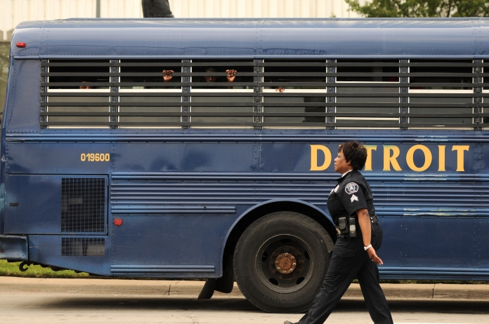 A teenager looks out of a Detroit Police bus after being detained for curfew violation on Monday evening ahead of the annual fireworks display, June 23. (Tanya Moutzalias/Special to the Detroit News)